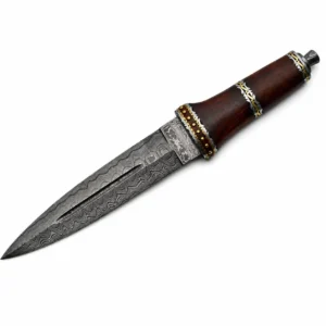 Close-up of a damascus steel fancy dirk blade showing the blood groove and brass guard filework.